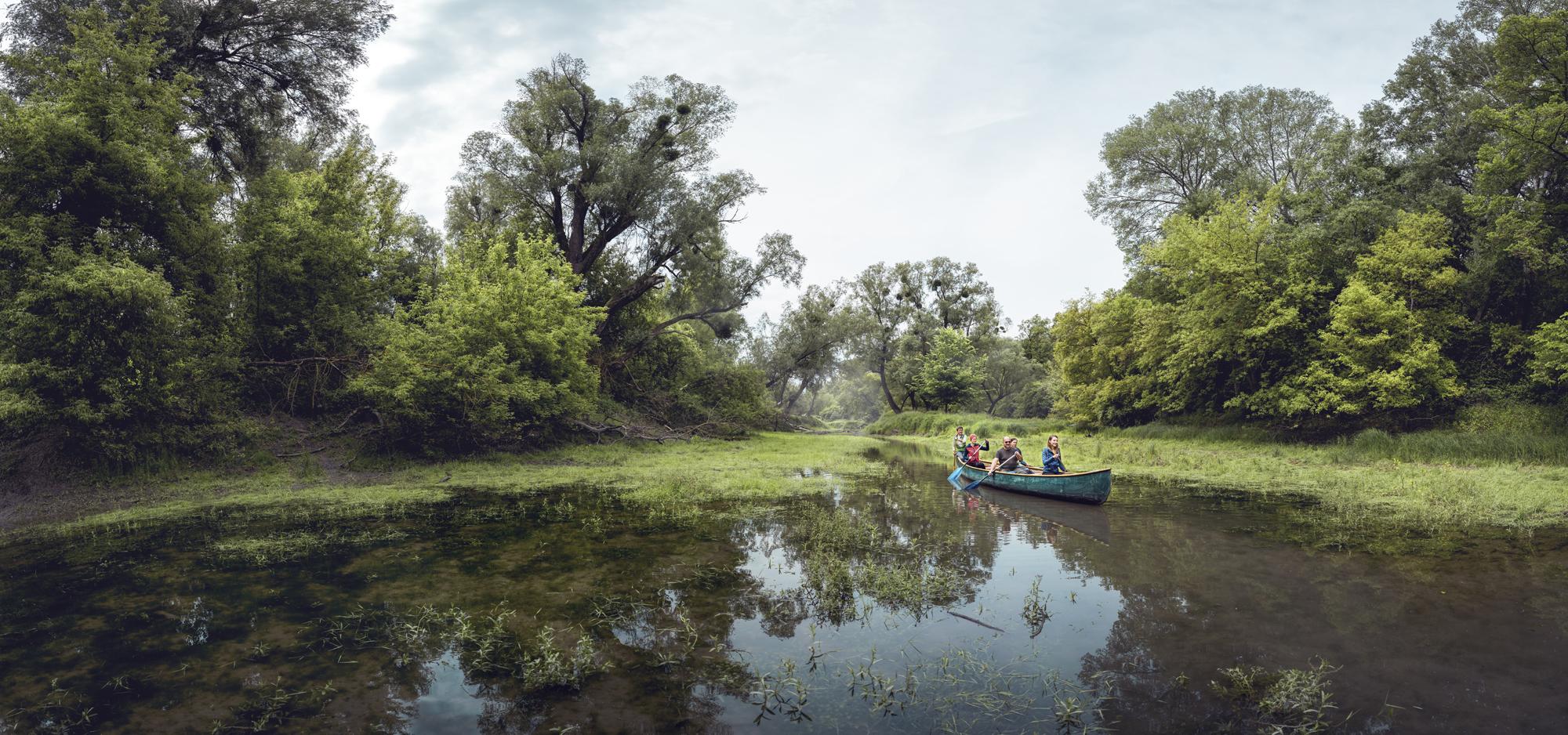 Menschen fahren mit einem Boot in einem Seitenarm der Donau.